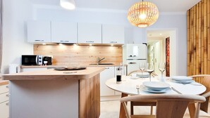 Een moderne keuken met witte kasten, een houten eiland en een eethoek met een ronde tafel en stoelen.