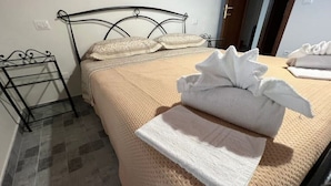 Un lit bien fait, avec une couverture et des oreillers de couleur beige, un cadre de lit en métal et une petite table de chevet avec une lampe.