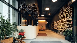 Een moderne receptie met een houten balie, potplanten en een decoratief wandontwerp.