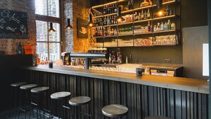 Een bar met een bakstenen muur, een houten toog en krukken.