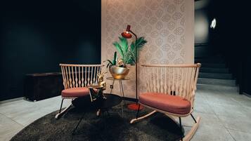 Une pièce avec deux fauteuils à bascule, une petite table et une plante en pot.