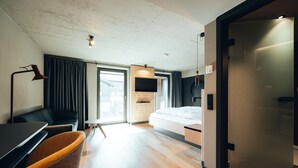 Een moderne hotelkamer met een houten vloer, een bed, een bureau en een stoel.