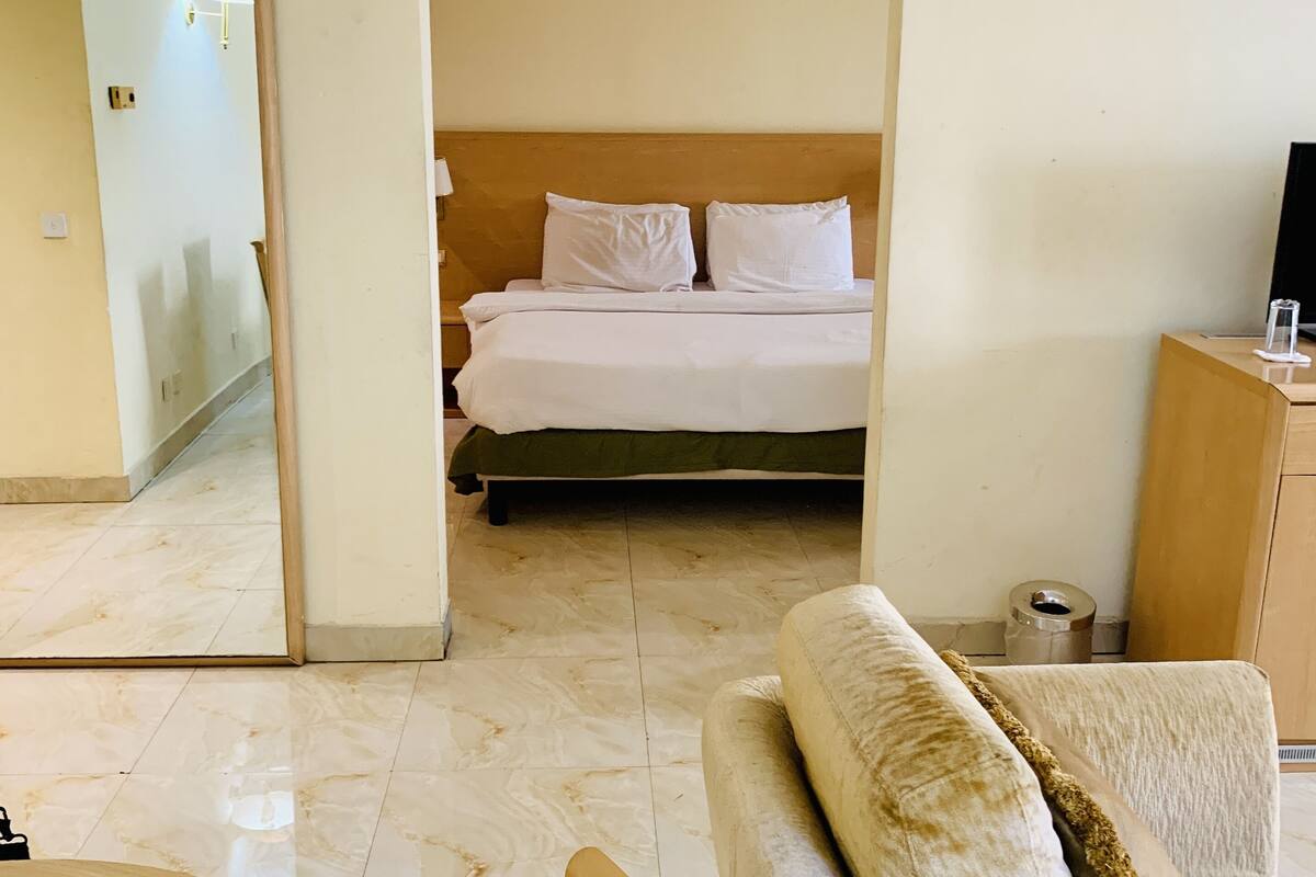 Una habitación de hotel con cama, sofá, una mesita y un espejo.