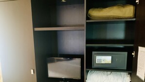Un armario de madera oscura con varios estantes, un televisor de pantalla plana y una pequeña caja fuerte.