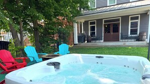 Ein Whirlpool im Garten, mit einem Haus im Hintergrund.
