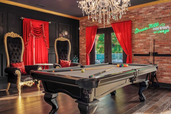 A billiards table with balls and cues, a pool table, and a neon sign reading "Green Mile Cocktail Lounge".