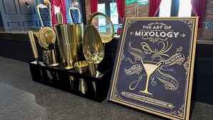 Een bar met een presentatie van cocktailshakers en een inlijsting boek getiteld 