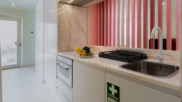 Een moderne keuken met een roestvrijstalen spoelbak, een schaal met fruit en een zwart draagbaar fornuis.