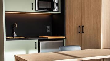 A modern kitchen with a wooden table, a black chair, and built-in appliances.