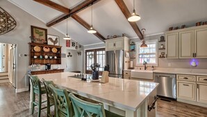 A spacious kitchen with a large island, wooden beams, and modern appliances.
