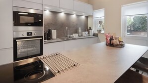A modern kitchen with built-in appliances, a large island, and a view of greenery outside.