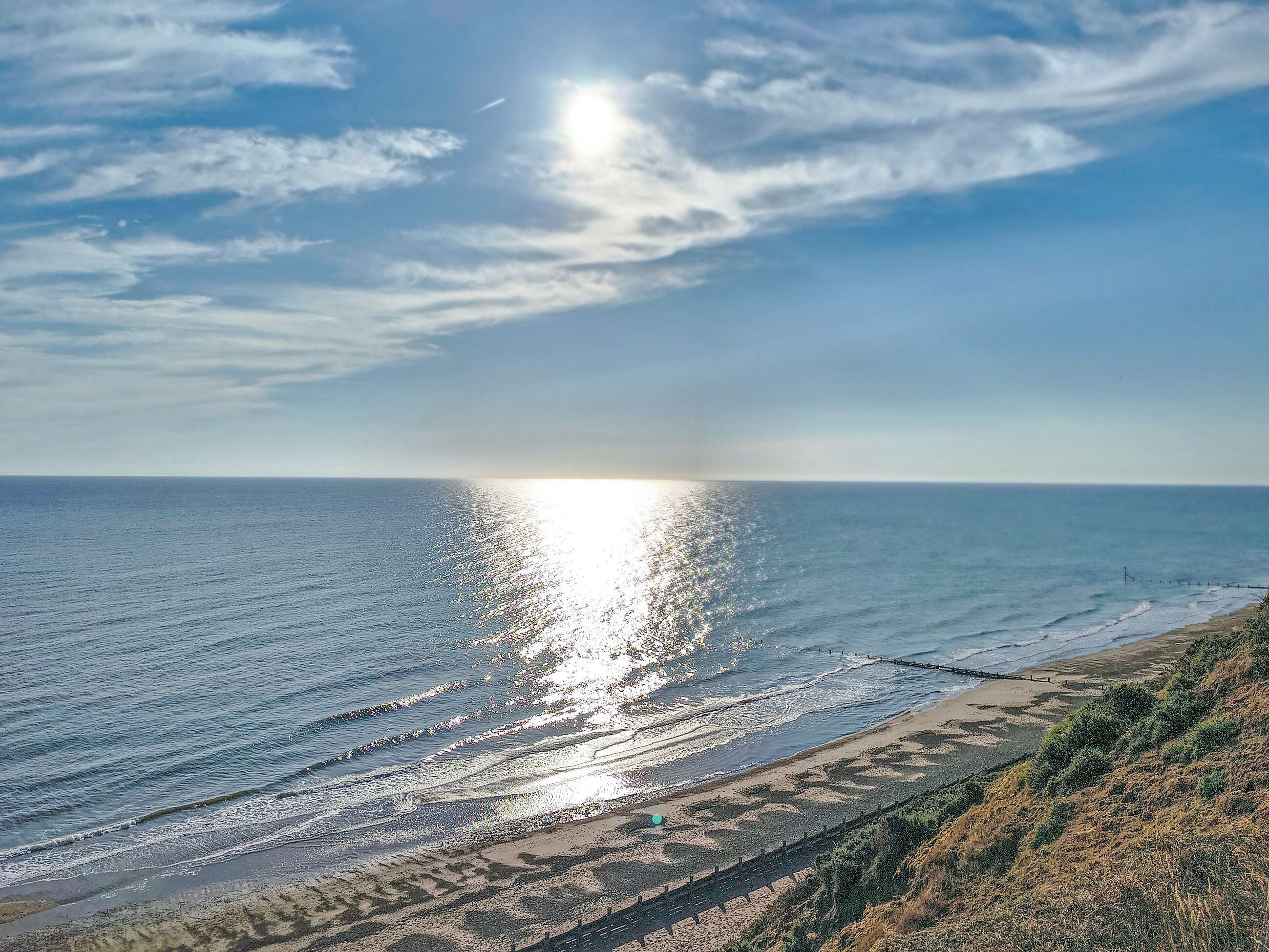 Un paysage côtier avec une plage, l’océan et un ciel dégagé.