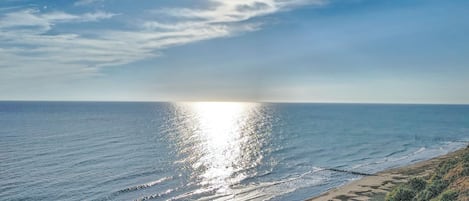 A coastal landscape with a beach, ocean, and a clear sky.