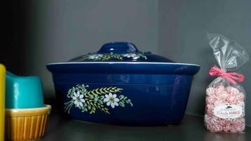 A blue container with floral designs and a plastic bag of pink candies.