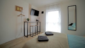 Una camera da letto moderna con un letto, una scrivania con due sedie, una TV e una finestra vista.