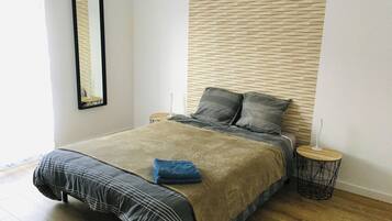 Une chambre à coucher avec un lit, une table de chevet, une lampe et un miroir au mur.
