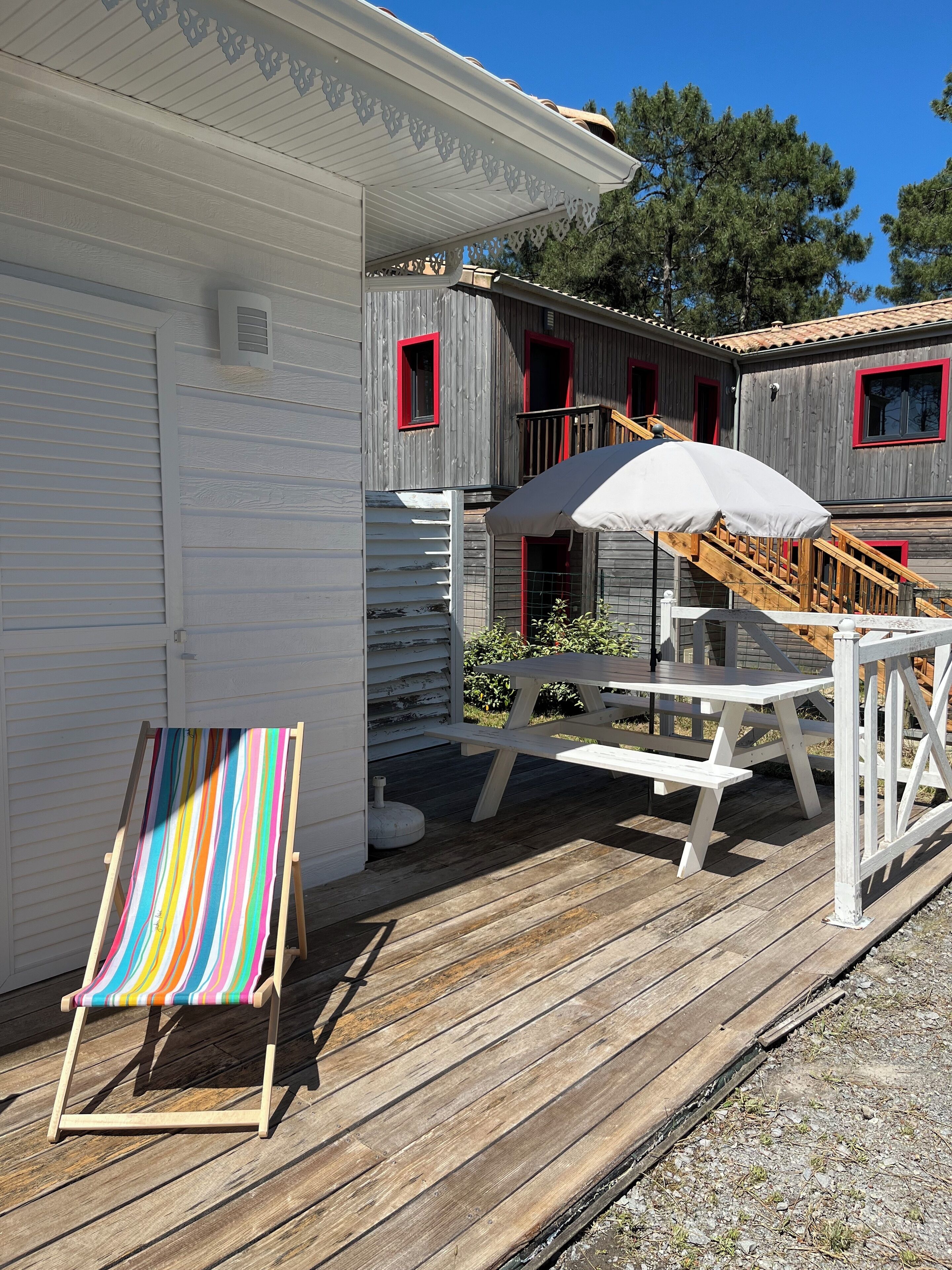 A wooden deck with a picnic table and a striped beach chair.