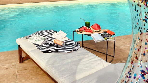 A poolside lounge area with a bench, a table with snacks, and a view of a stone wall with trees. - "maison56"- Maison Cosy, Piscine, Entre Blois-chambord, 4 Chb, Proche Loire (Montlivault)