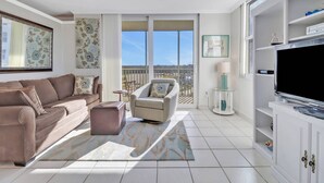 A modern living room with a sofa, armchair, and a flat-screen TV. - Beach & Tennis 1501 (Bonita Springs)