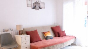Une chambre à coucher comprenant un lit, une chaise, une table de chevet, une lampe, un ventilateur de plafond et un mur décoré d’œuvres d’art.