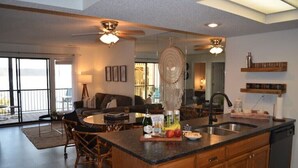 A modern kitchen with a large island, wooden cabinets, and a built-in dishwasher. - Lakeside Boho Bungalow on Table Rock Lake (Kimberling City)