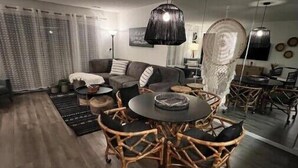 A modern living room with a round dining table, wicker chairs, a sofa, and a large mirror. - Lakeside Boho Bungalow on Table Rock Lake (Kimberling City)