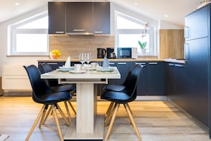 A modern kitchen with dark cabinets, a wooden dining table, and black chairs. - Newly decorated apartment for two persons (Sveti Anton)