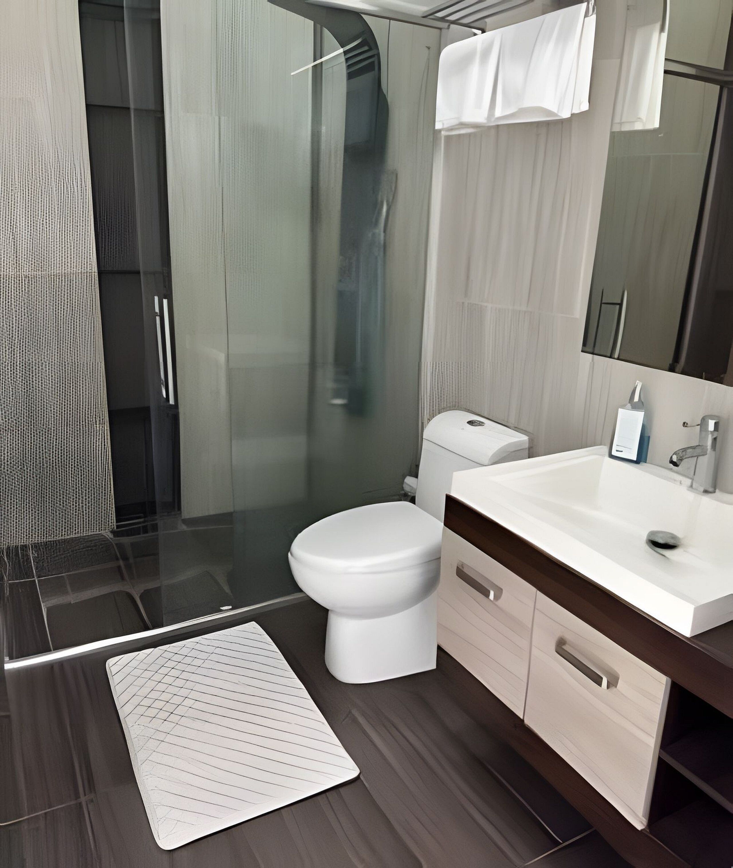 A modern bathroom with a glass shower enclosure, a white toilet, and a vanity with a mirror.