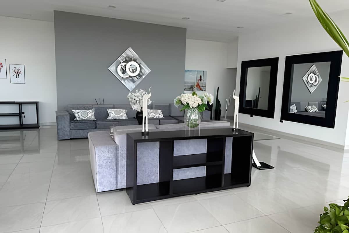 A modern living room with a grey sofa, a black and grey console table, and a vase with flowers.