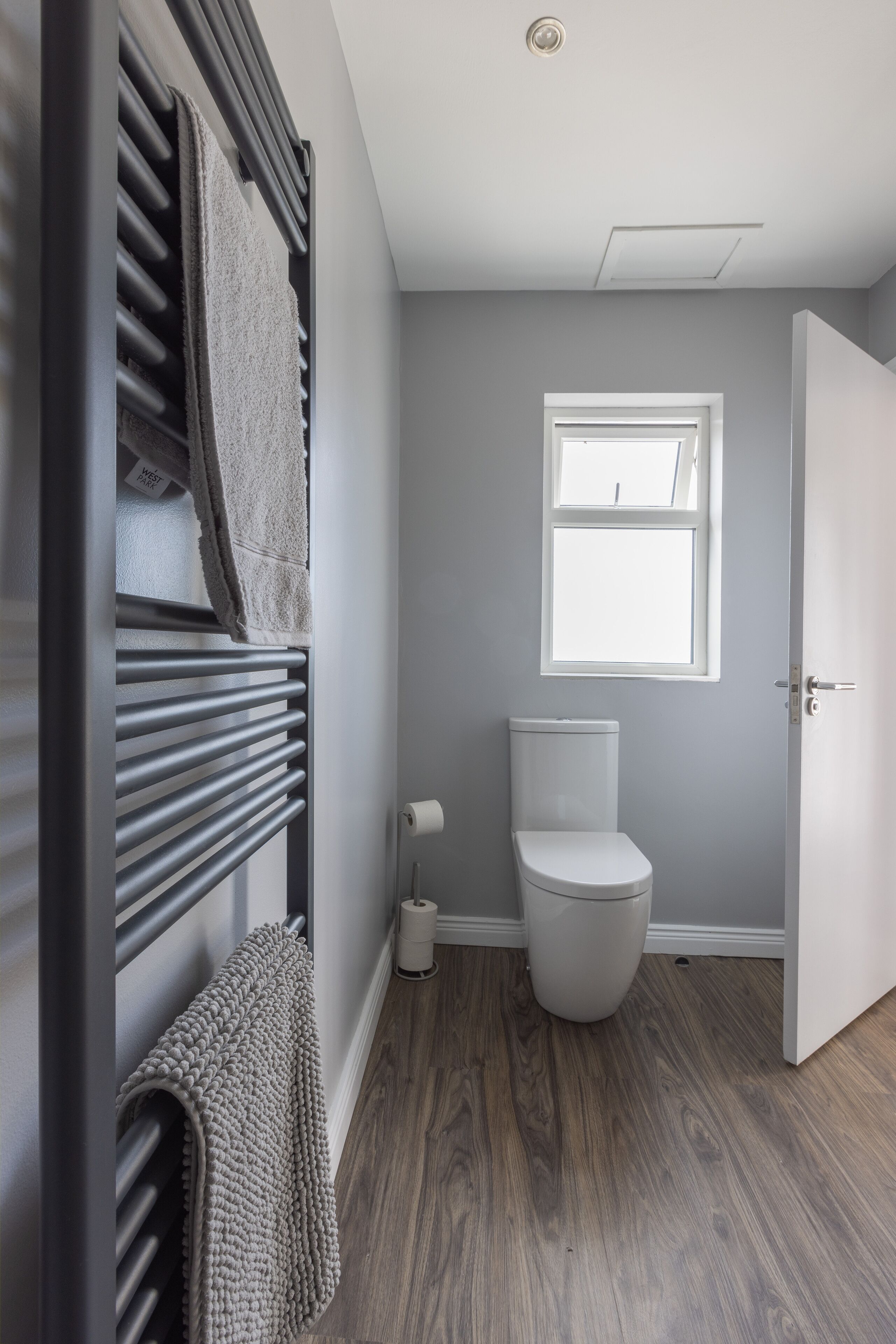 Un bagno con il water, un portasciugamani, una finestra e una porta.