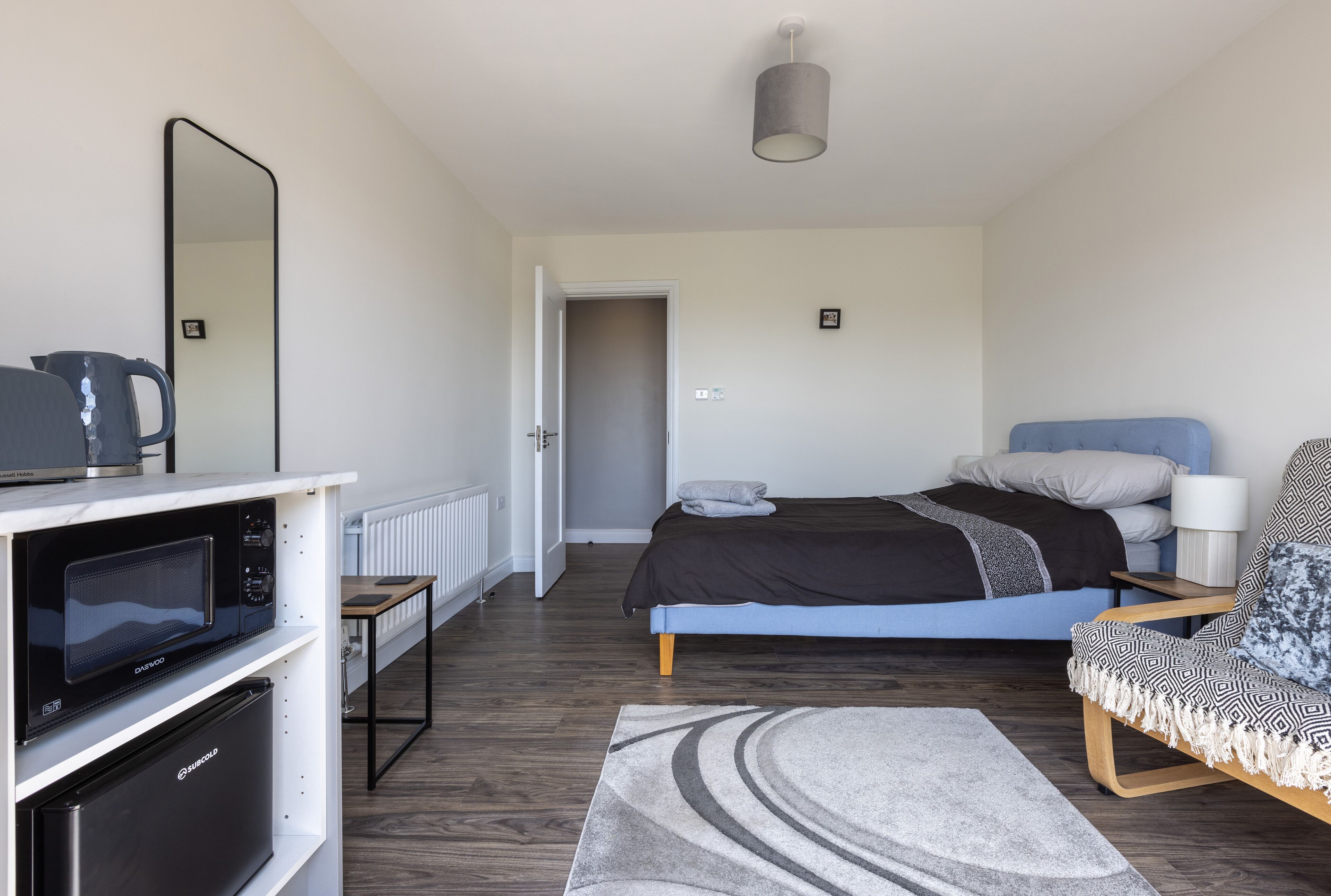 Un dormitorio moderno con cama, sofá, microondas y refrigerador.