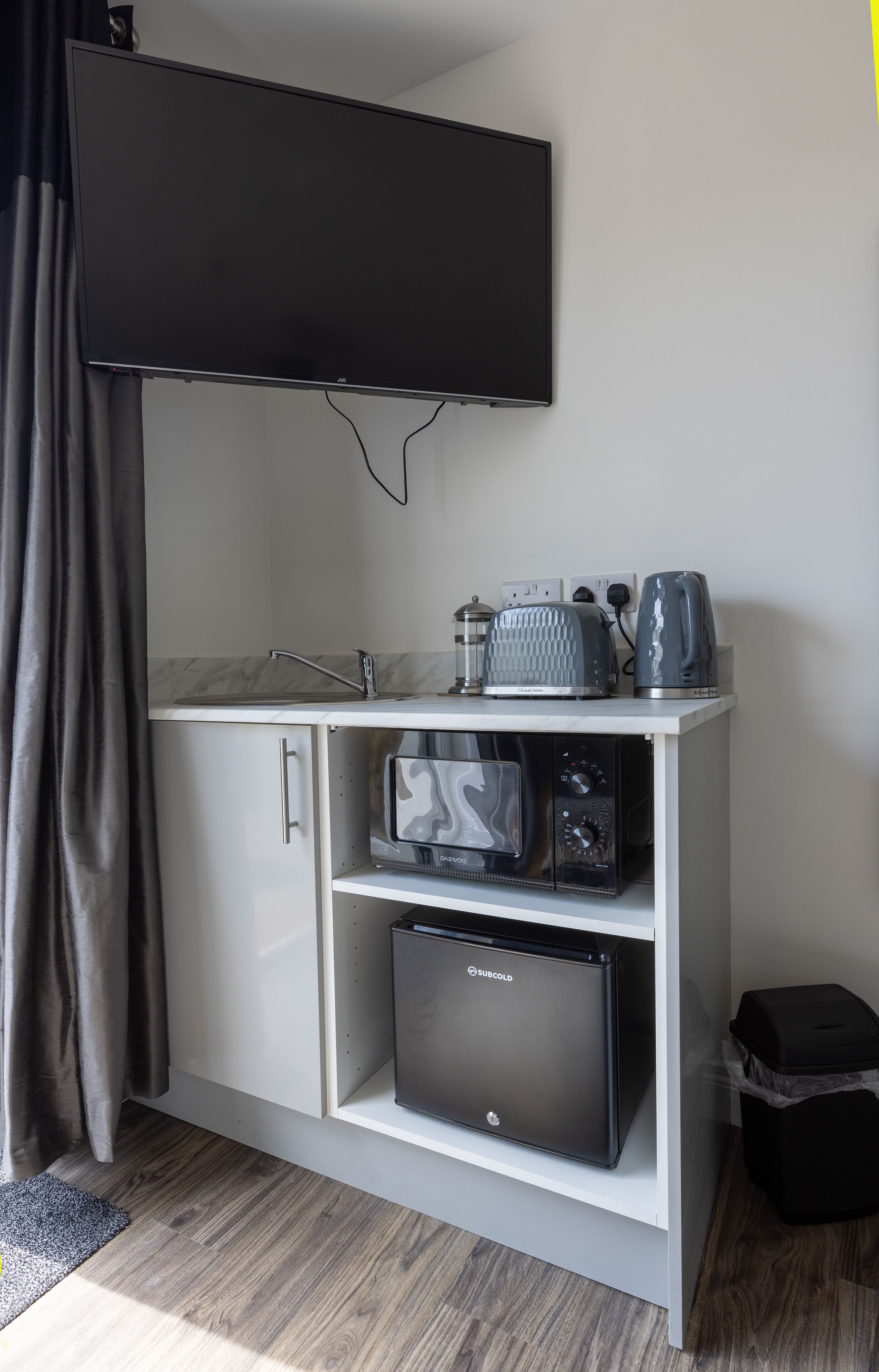 A compact kitchenette with a flat-screen TV, a microwave, a toaster, and a refrigerator.