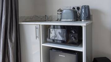 A compact kitchenette with a flat-screen TV, a microwave, a toaster, and a refrigerator.