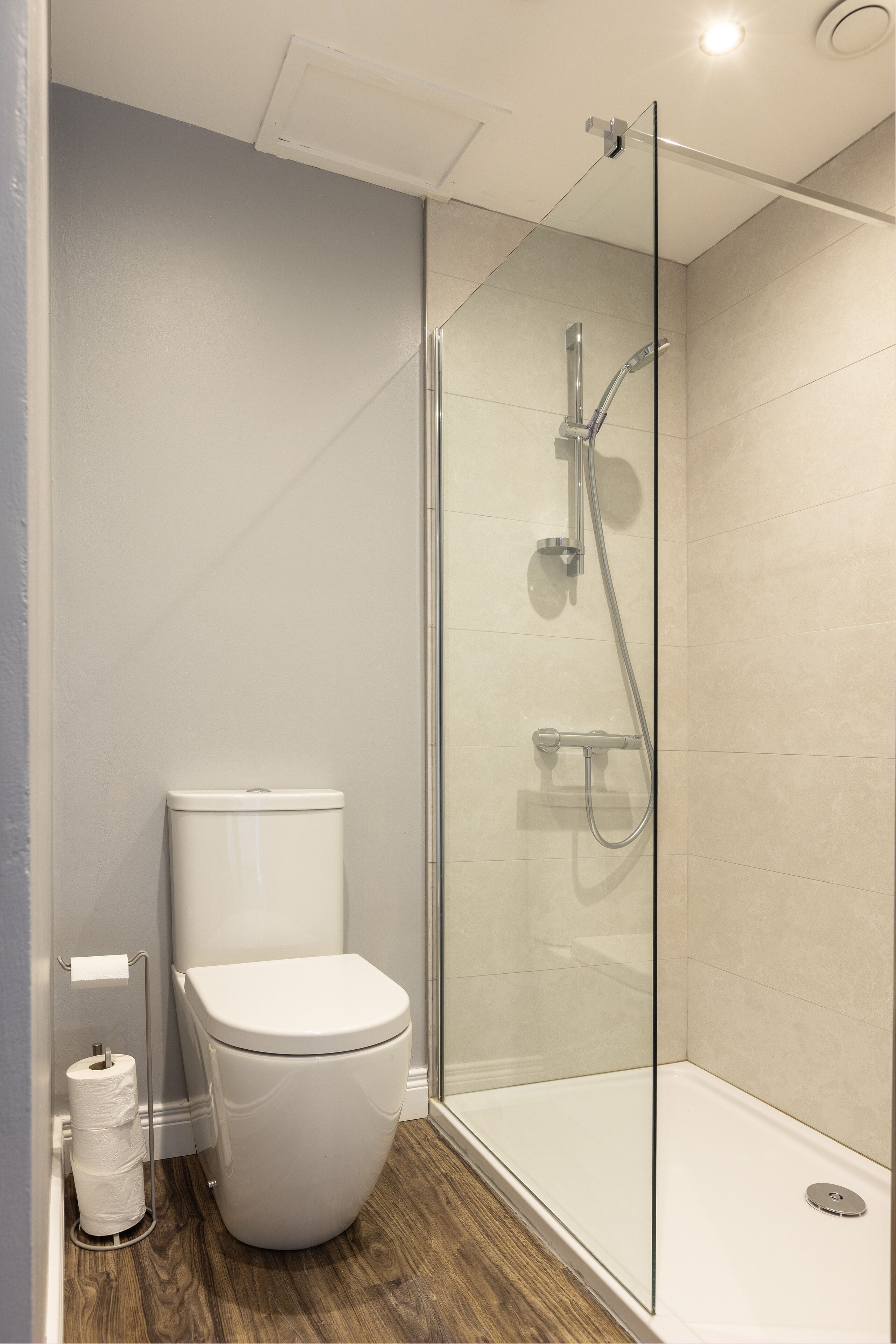 Ein modernes Badezimmer mit einer Duschkabine, einer Toilette und einem Holzboden.