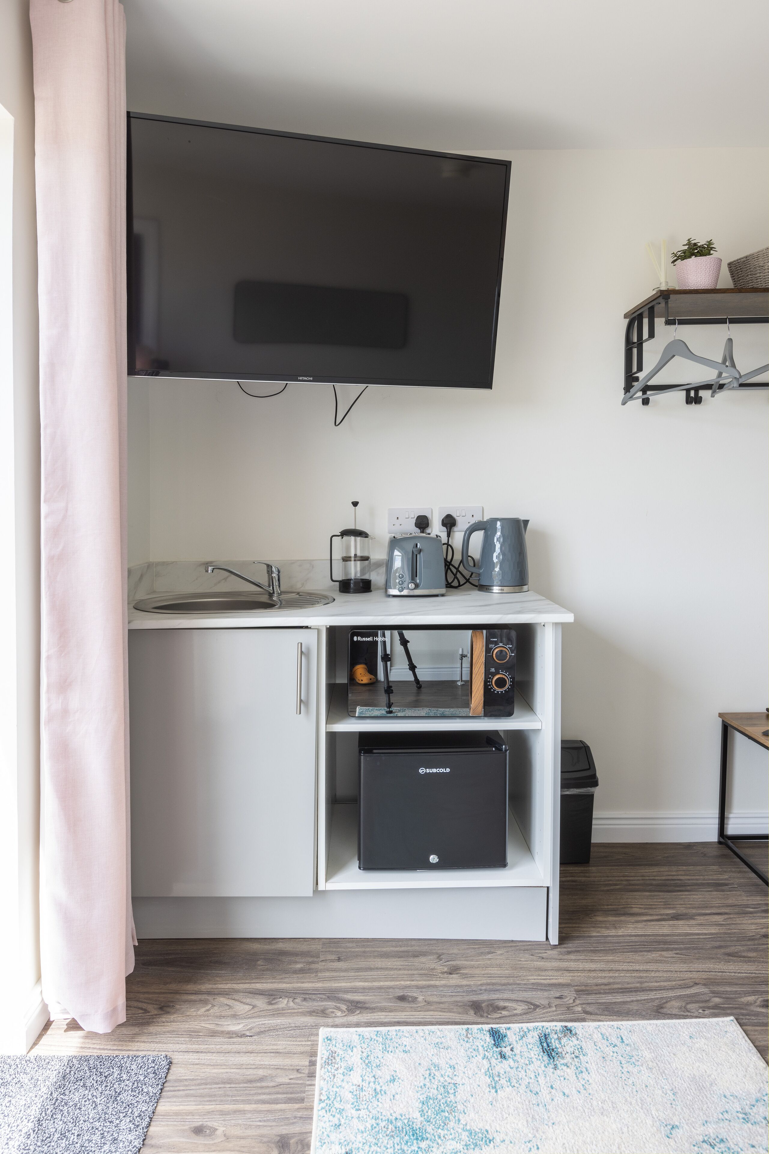 Un angolo cottura compatto con TV integrata, macchina del caffè, bollitore ed un tostapane.