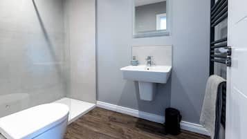 Un baño moderno con inodoro, lavamanos y ducha.