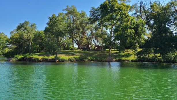 A lakeside property with a small cabin surrounded by trees. - Tiny Home at Camp Mahanaim - New Paris, OH   -  Private Lake  (New Paris)