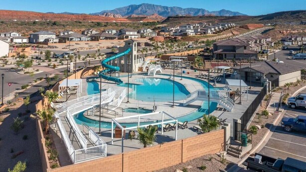 A swimming pool with a slide, surrounded by a parking area and residential buildings, with mountains in the background. - 30 people with pool, waterslide and pickleball (Washington)