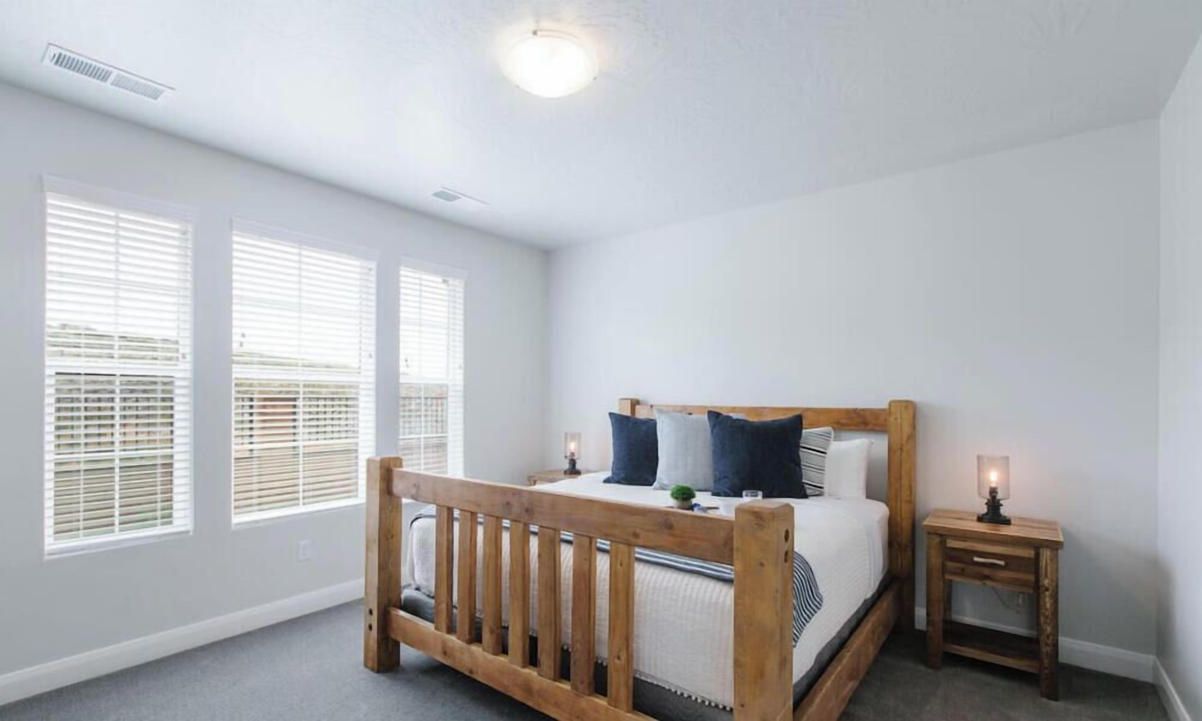 A bedroom with a wooden bed, white walls, and a small bedside table with a lamp.