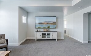 A room with a large window, a white cabinet, and a painting on the wall.