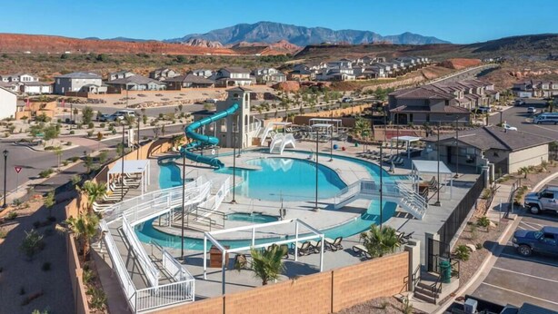 Piscina com escorregador, rodeada por um estacionamento e edifícios residenciais.