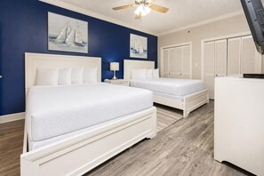 A bedroom with two beds, a ceiling fan, and a TV.