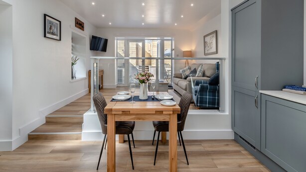 A modern kitchen with a dining area, a TV mounted on the wall, and a view through the glass door. - 1 bedroom accommodation in Consett, County Durham (Consett, County Durham)