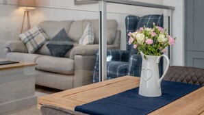 A modern living room with a sofa, a coffee table with a vase of flowers, and a glass railing. - 1 bedroom accommodation in Consett, County Durham (Consett, County Durham)