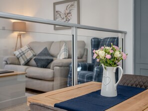 Ein modernes Wohnzimmer mit einer Couch, einem Couchtisch mit Blumen und einer Glastrennwand.