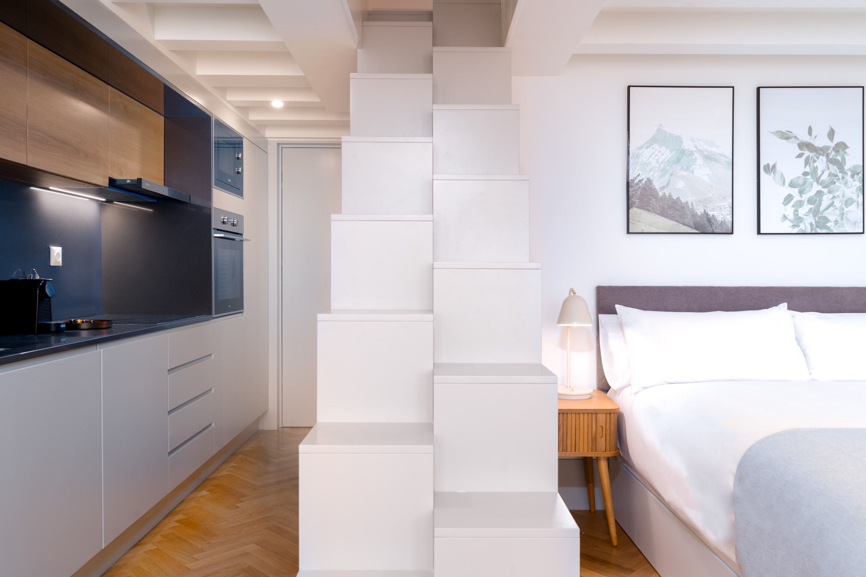 Una habitación de hotel moderna con cocina, una escalera y una cama.