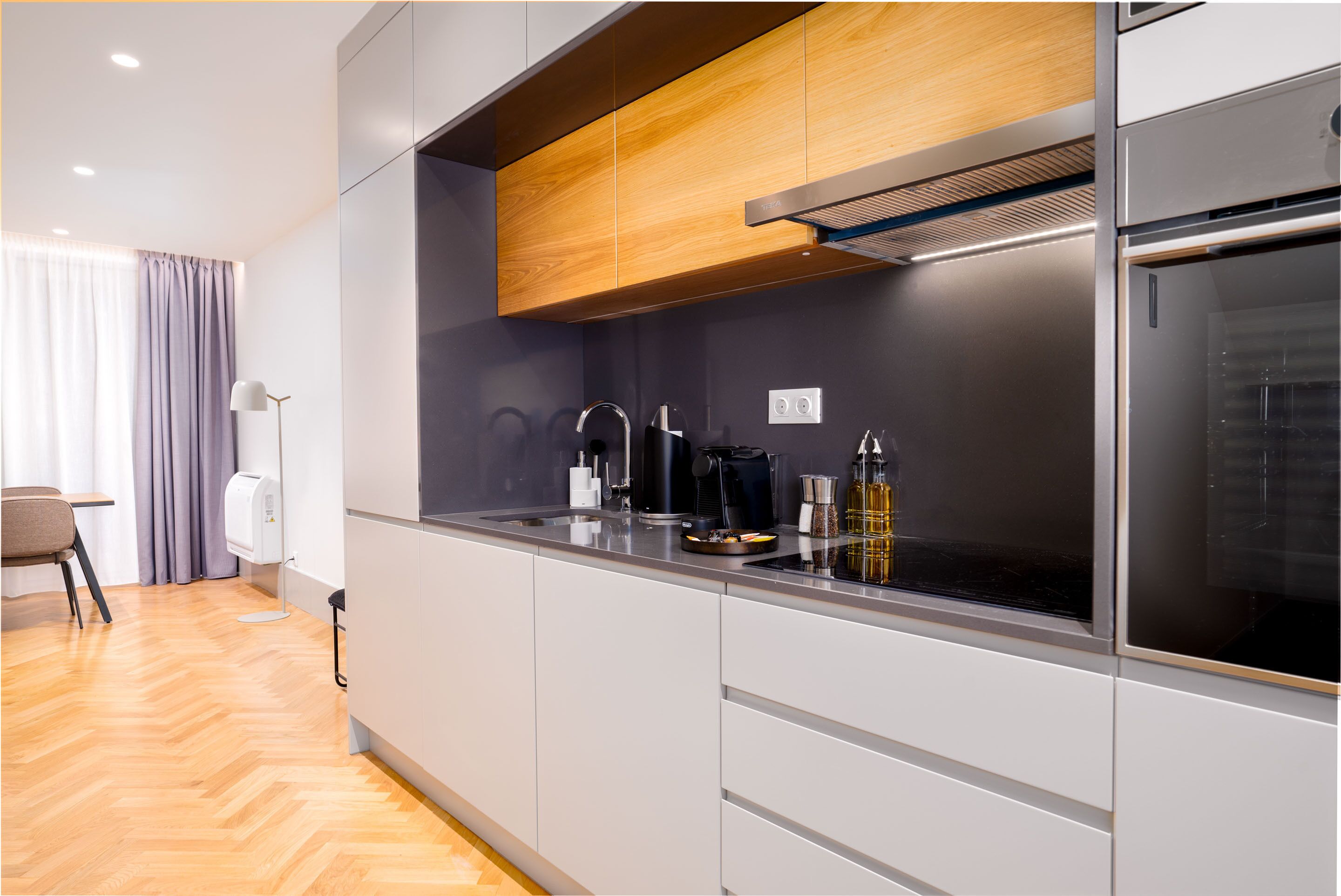 Een moderne keuken met een ingebouwde oven, een koffiezetapparaat en een waterkoker.