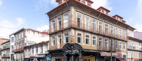 Edificio histórico con arquitectura ornamentada, varios balcones y una tienda en la planta baja.