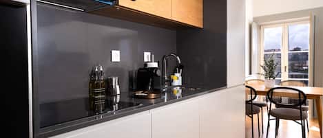 A modern kitchen with a black countertop, white cabinets, and a wooden ceiling.