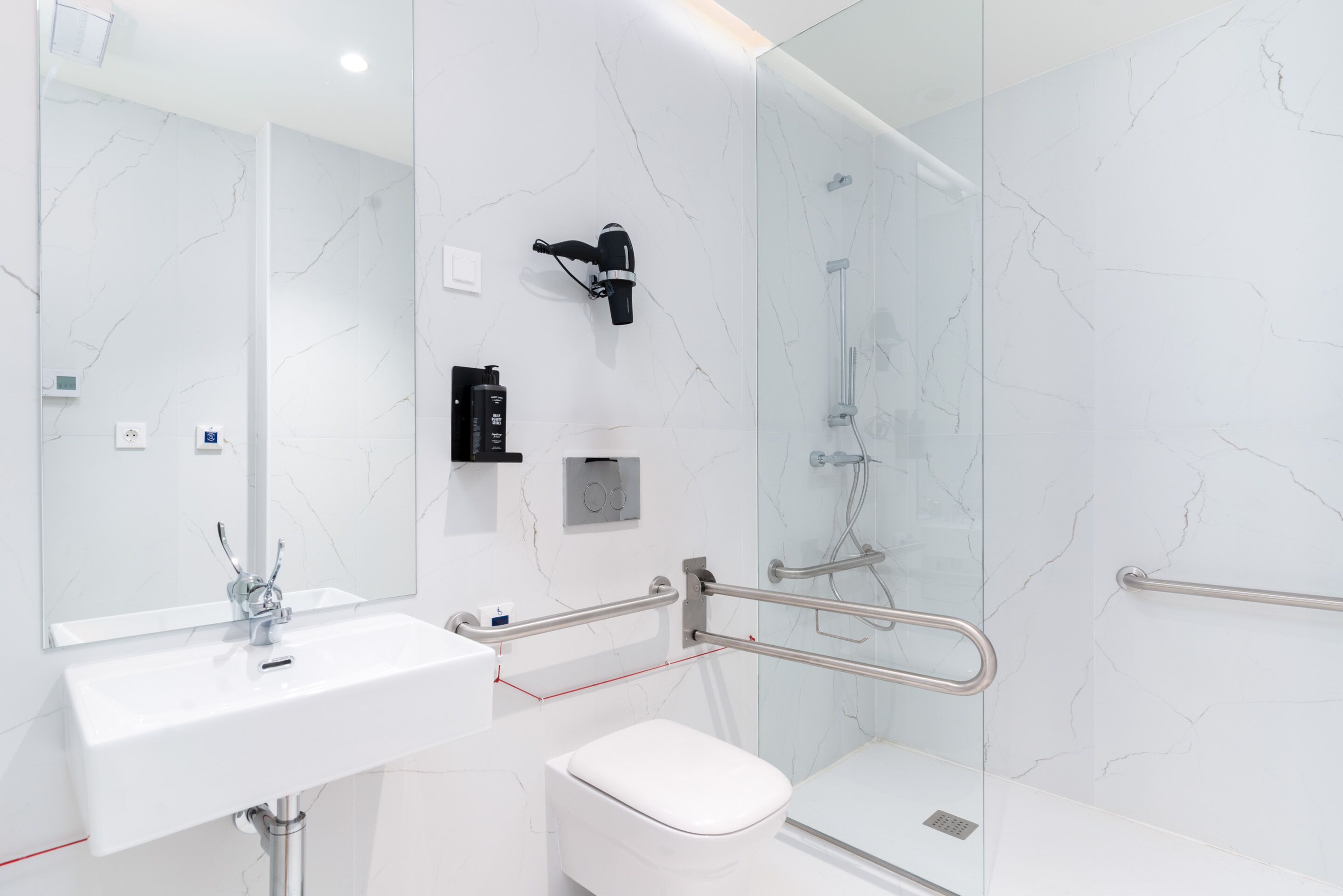 A modern bathroom with a white sink, toilet, and glass-enclosed shower area.